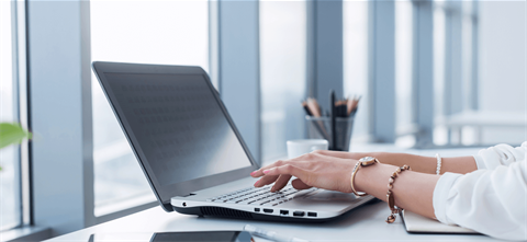 Hands typing on a laptop